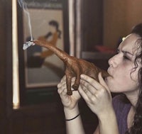 a woman smoking a dinosaur shaped cigarette