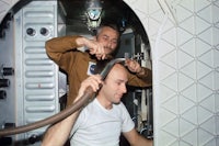 two men in a space station with a hose